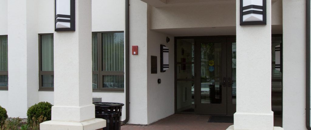 A closer look at Clinton Manor's covered entrance, showing the handicap-accessible, door switches and security call button.