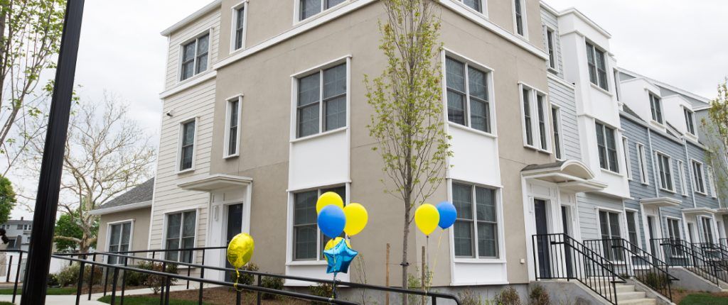 The new buildings feature many windows, private entrances, and a chic exterior of concrete, siding, and architectural elements.