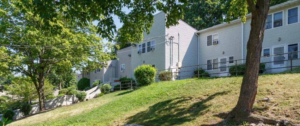 A view from below the multi-level townhouses from the grassy area. There are plenty of windows and exterior lighting.