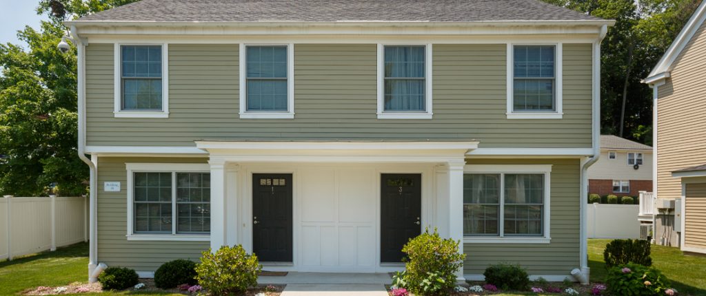 Green grass wraps around the building, and flowers and shrubbery grace the front entrance. Trimmed windows let the sun in.