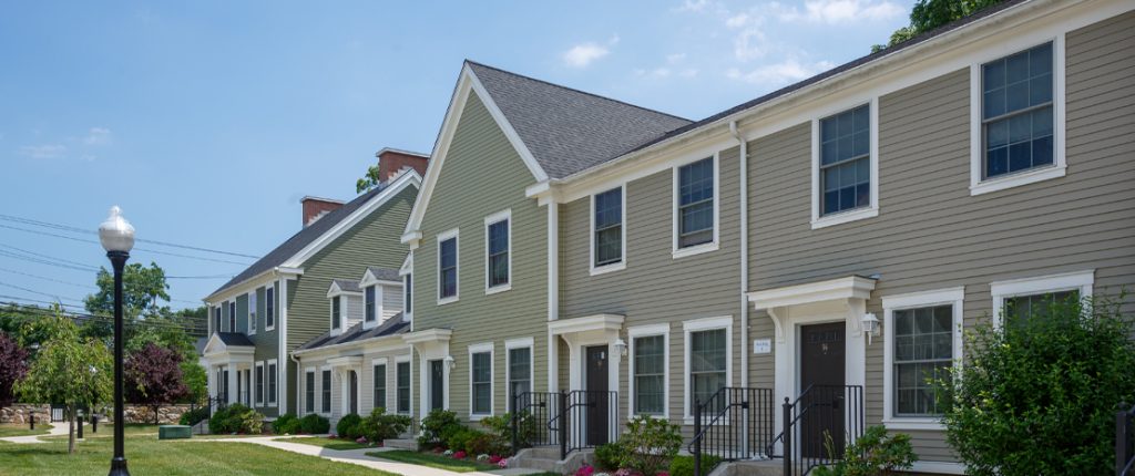 The long Colonial-style unit showcases the beautifully manicured landscape and private entrances outfitted with door lamps.