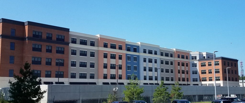 The large building looks chic with differently colored, smooth facades capped by brick exterior on both sides.