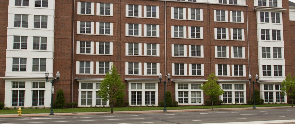 Small trees and lamp posts line the street outside of the mixed brick facade and many windows of Post House.