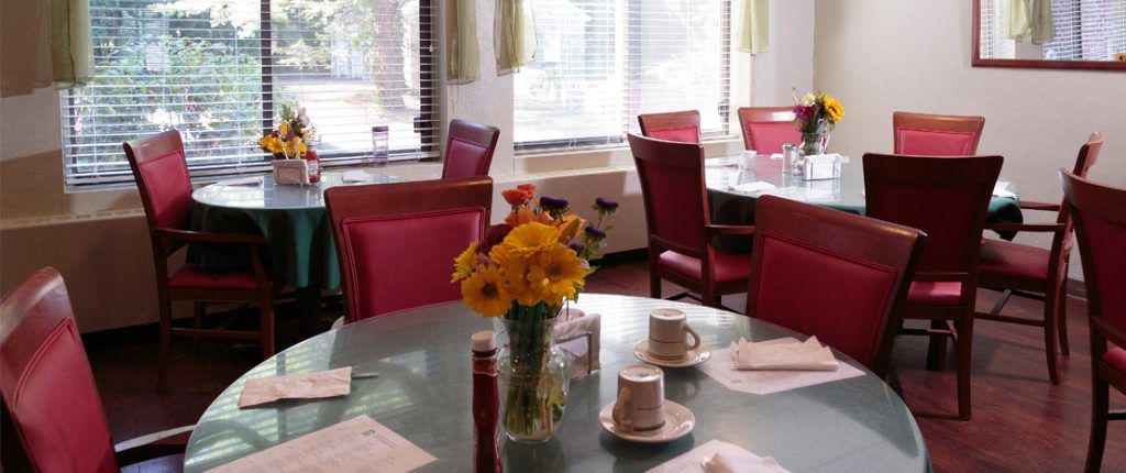 Natural light streams into the dining area, plenty of space exists between the inviting tables topped with fresh flowers.