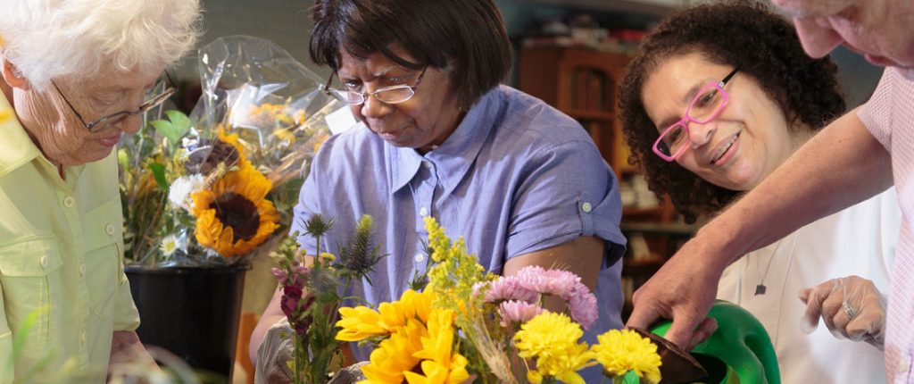 A group of senior residents work together to create the flower arrangments placed around this residential care facility.