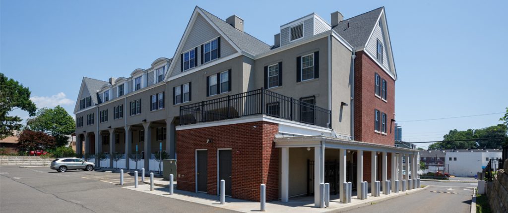 The rear view shows a contemporary exterior of smooth concrete and brickwork. The many windows have faux shutters.