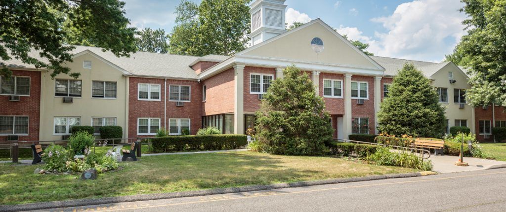 This view of Wormser Congregate shows a small garden area, in-wall AC units, and a wheelchair accessible walkway.