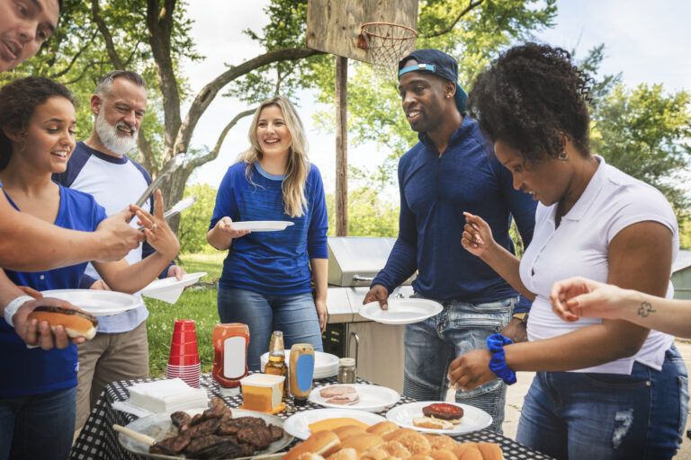 Group gathers outdoors for a community BBQ, sharing food and conversation in a friendly, welcoming environment.